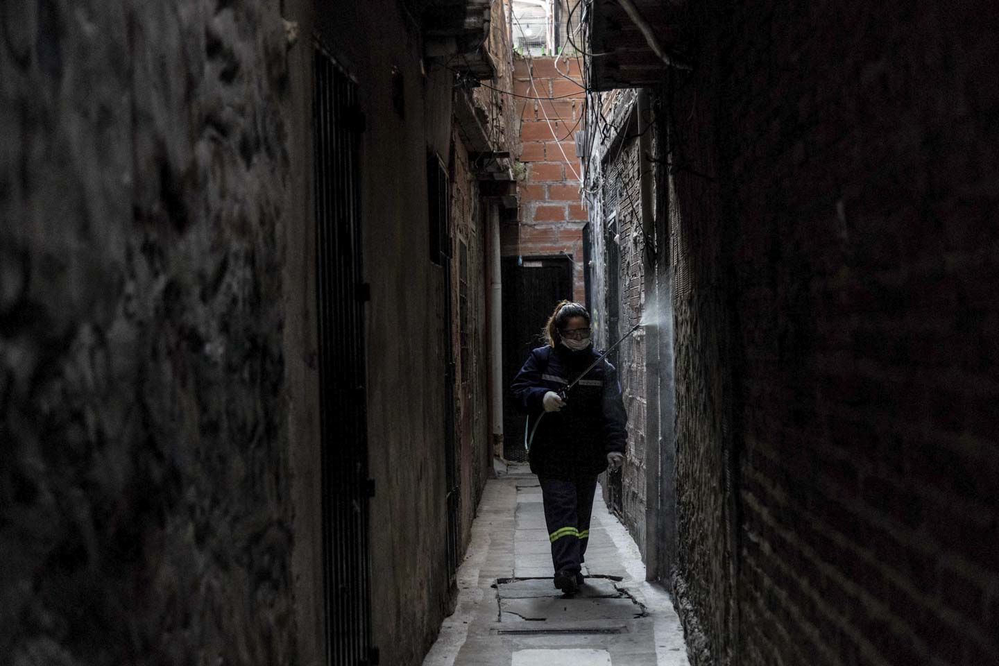 A member of the cleaning cooperative disinfecting the narrow alleys of the slum. Image by Anita Pouchard Serra. Argentina, 2020.