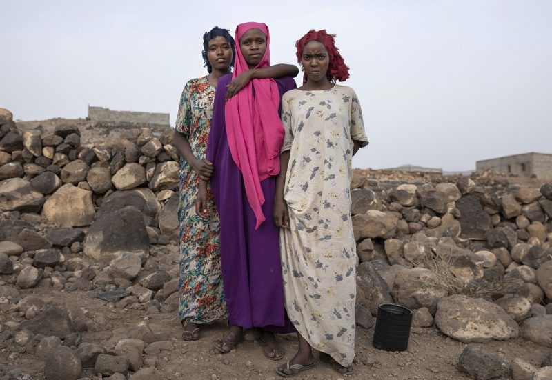 Sixteen-year old Ethiopian migrants from left, Safeya, Ikram, and Hamdiya, pose for a portrait, July 12, 2019, at a slum in Dikhil, Djibouti, where they took shelter after entering the country on their journey intended to take them to Yemen and Saudi Arabia. The 100-mile (120-kilometer) trip across Djibouti to the water can take days. Many migrants end up in the country's capital, living in slums and working to earn money for the crossing. Young women often are trapped in prostitution or enslaved as servants. Image by AP Photo / El-Mofty. Djibouti, 2019.