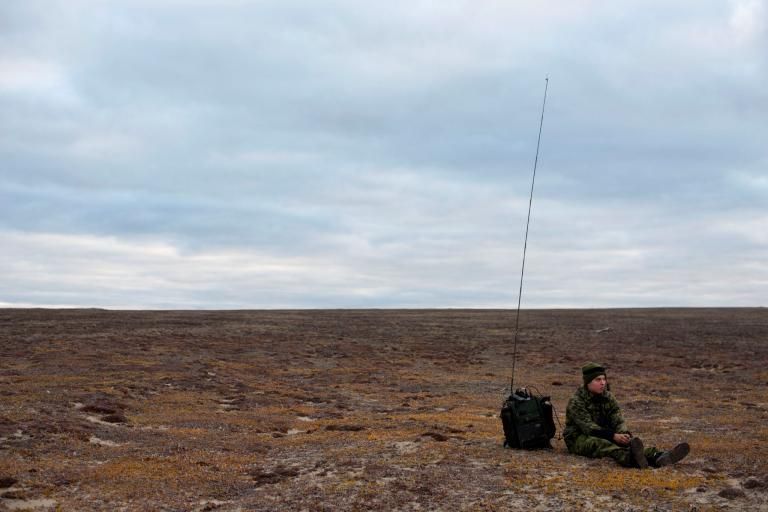 A soldier waits by his radio on the tundra near Blue Fox Harbor on Banks Island in the Canadian Arctic. The soldier was part of Operation Nanook, an annual “sovereignty operation,” in which Canadian forces patrol the nation’s northern territory. Image by Louie Palu. Canada, 2018.