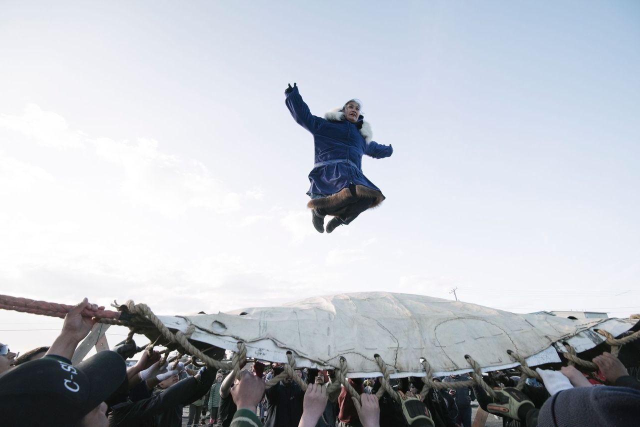 In a festival tradition that goes back millennia, Inupiat villagers join together to toss successful whalers into the air to celebrate a successful whaling season and to give thanks to the whale for its gift. Image by Kiliii Yuyan. United States, undated.