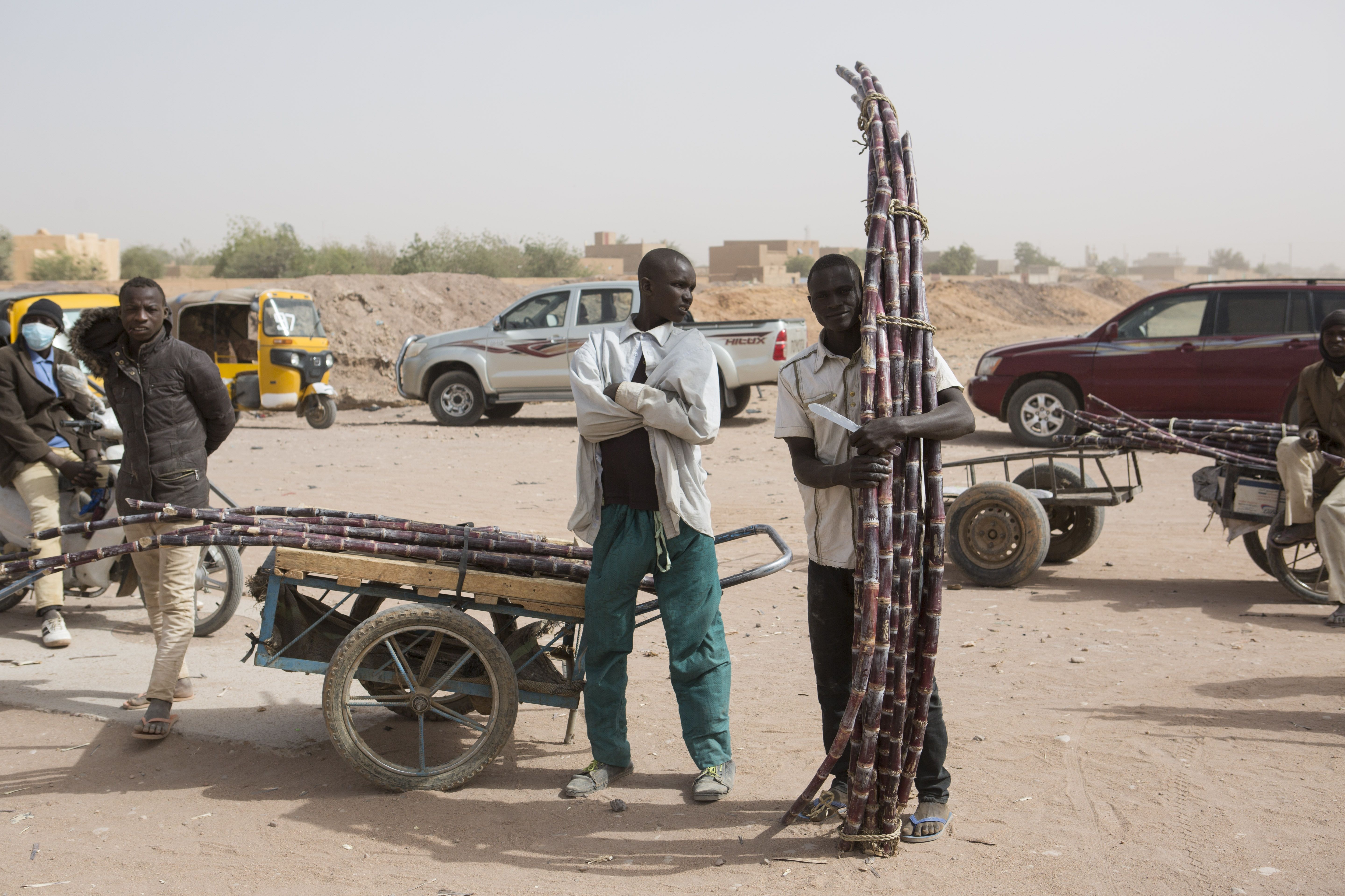 Sugarcane vendors stand outside during a ceremony at a police station in Agadez, Niger, Jan. 15, 2018. Image by Joe Penney. Niger, 2018.