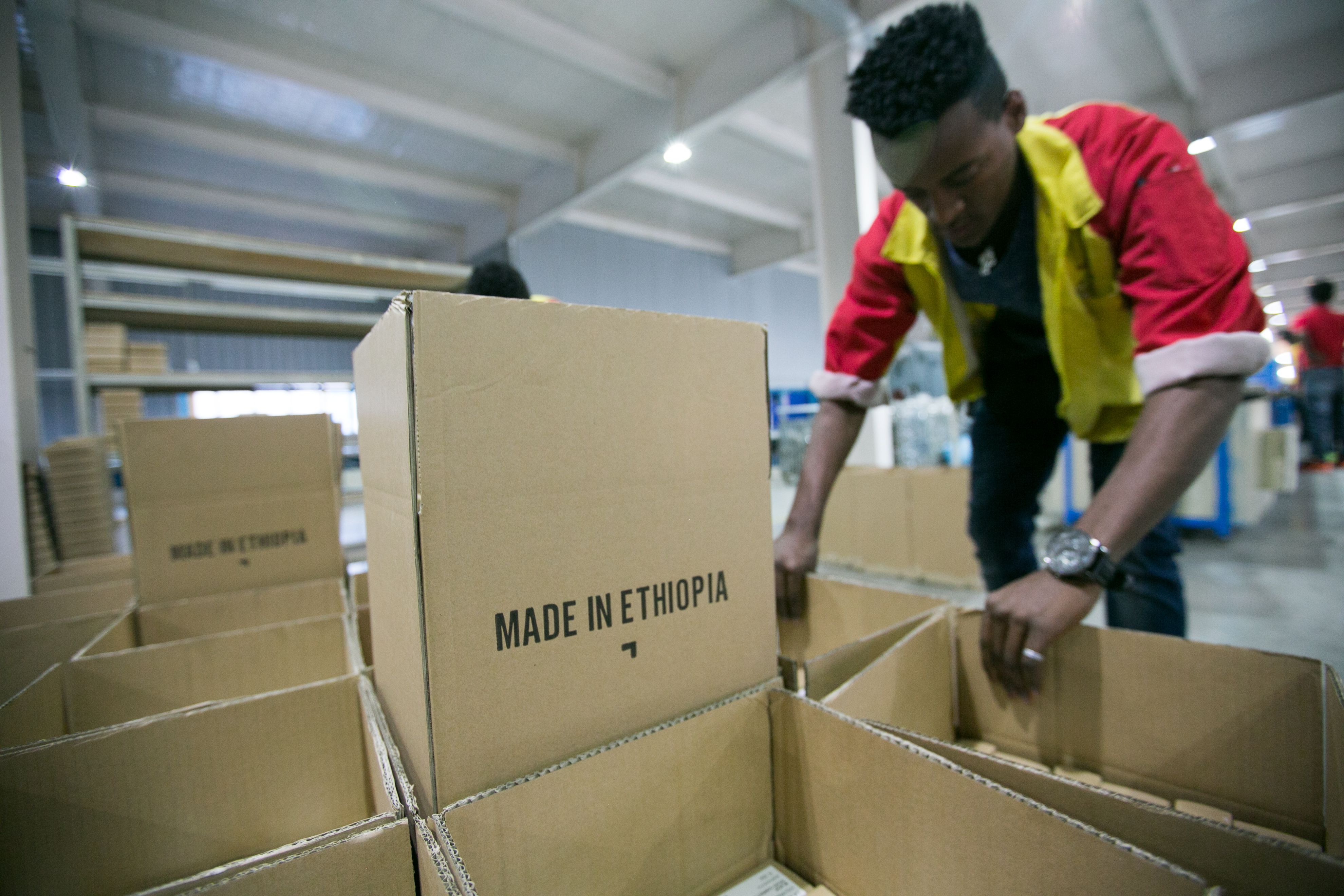 An Ethiopian worker fills boxes with shoes from the Huajian assembly line. Many of the shoes manufactured here are sold in the United States. Image by Noah Fowler. Ethiopia, 2017.