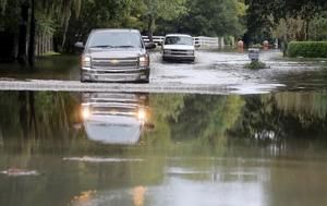 Motorists make their way down a flooded Winners Circle, in Hickory Farms in the Church Creek area. Image by Brad Nettles/The Post and Courier Staff. United States, undated.
