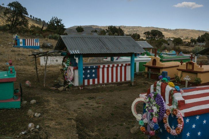 Graves painted with the U.S. flag, in the cemetery of Todos Santos Cuchumatán, indicate that the deceased died as immigrants in the U.S. The families paint the flags as a symbol of thanks for money that their loved ones sent home from the U.S. Image by Mauricio Lima. Guatemala, 2019.