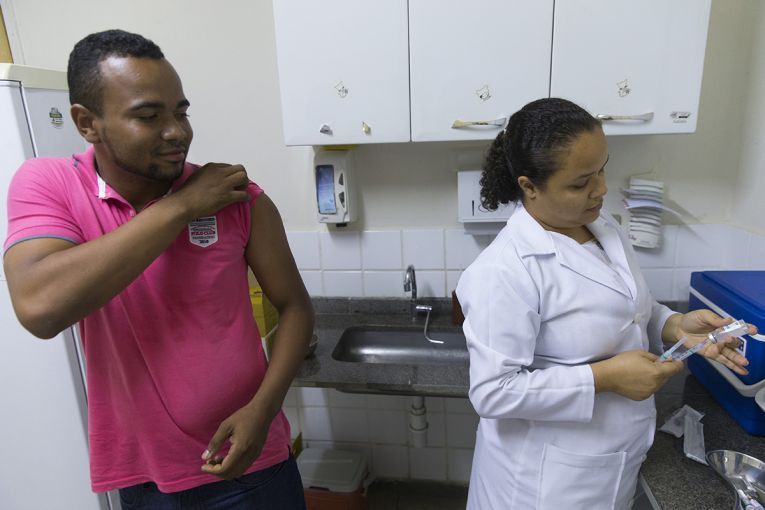 Delvid Santos Melo prepares to receive a yellow fever immunization from clinic worker Tielly Barboga de Souza. Image by Mark Hoffman. Brazil, 2017.