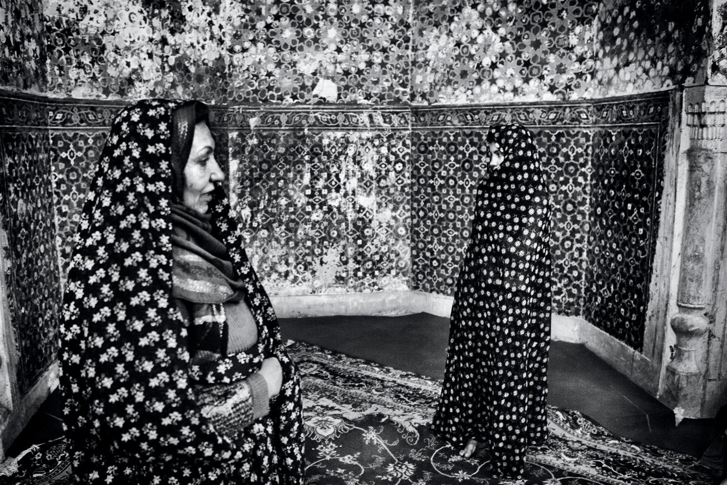 An afghan woman (left) and her daughter, refugees in Iran, visit a Sufi saint on a trip to their homeland. Image by Monika Bulaj. Afghanistan, 2010.