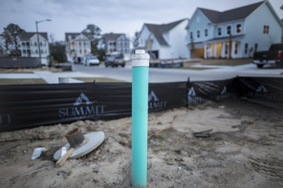 A green PVC sewage clean-out pipe sticks out of the ground at a construction site at Turner's Pointe on Whitemarsh Island. New homes at the development, just a few blocks southeast of the Scotts' neighborhood, will be connected to the municipal sewerage system. In order to develop that property, the developer had to tap into the sewage lift station on the other side of Highway 80. Image by GPB Photo / Stephen B. Morton. United States, 2020.