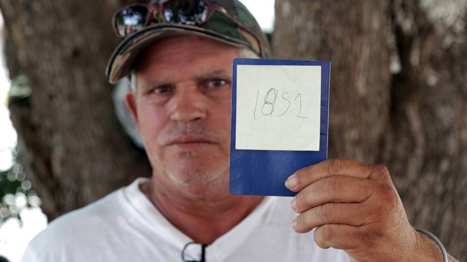 Jorge Luis Fleites, a Cuban migrant currently waiting in Matamoros, Mexico, for his chance to ask for asylum in the United States, holds up his number in line. He has been waiting for two months since he arrived at the border and was hoping to be able to get in in the next few days after this photo was taken. Image by Jose A. Iglesias. Mexico, 2019.