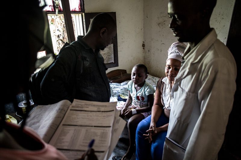 Health workers in Aloya try to convince a mother to send her child to an Ebola treatment centre. Image by John Wessels. Democratic Republic of Congo, 2019.
