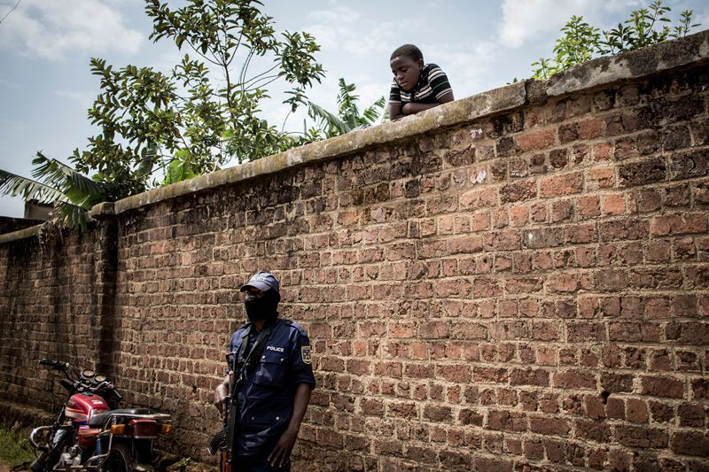 A police officer stands guard outside a clinic in Katwa. Image by John Wessels. Democratic Republic of Congo, 2019.
