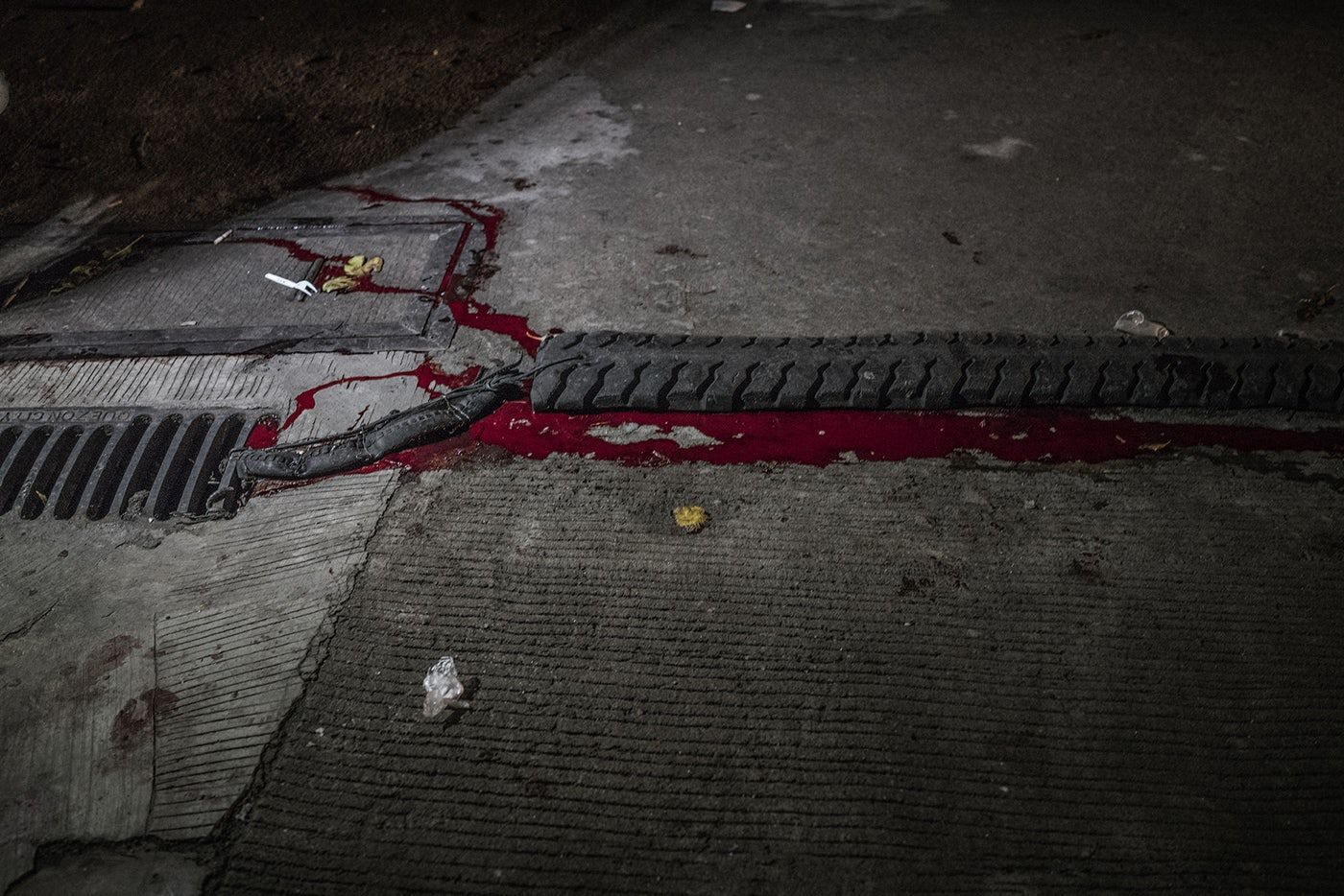 Manuel Borbe’s blood runs into a storm drain after he was killed by unidentified masked men on motorcycles in the Holy Spirit district of Quezon City. According to his sister, Vivian, Borbe dealt drugs, but not by choice; he was forced into the drug trade to support his addiction to methampetamines, known locally as shabu. Image by James Whitlow Delano. Philippines, 2017.