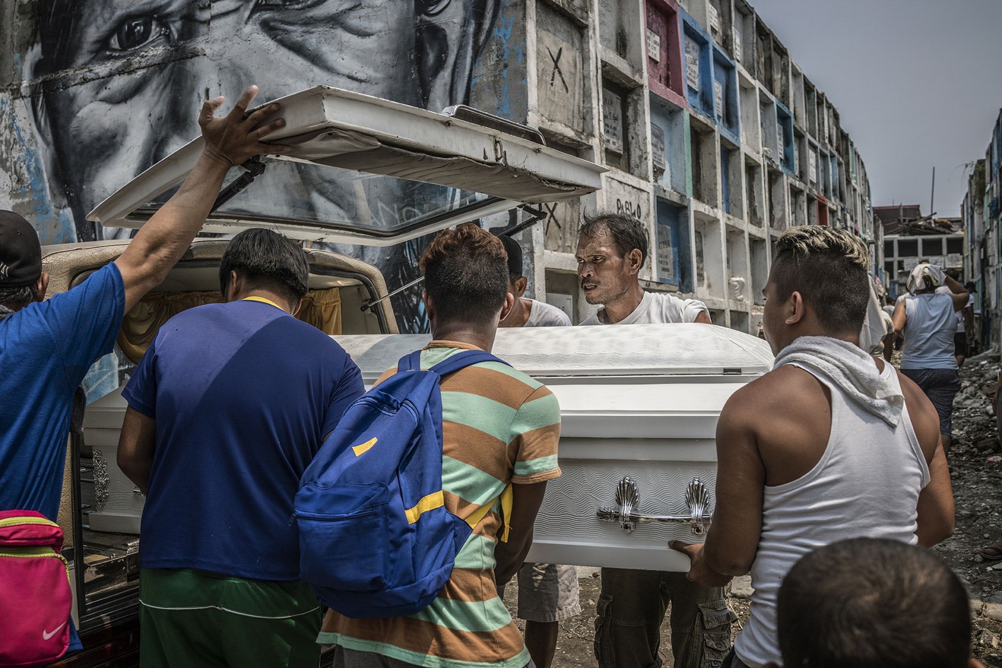 Family and friends lift a coffin carrying Junmar Abletes—another victim of an extrajudicial killing—out of a hearse in Navotas’s Catholic Cemetery. Abletes, who was 27 when he died, had moved to the island of Samar, over 370 miles away from his home in Metro Manila. While back on a family visit, he was assassinated in the Market 3 slum in Navotas, where his family lives. Image by James Whitlow Delano. Philippines, 2017.