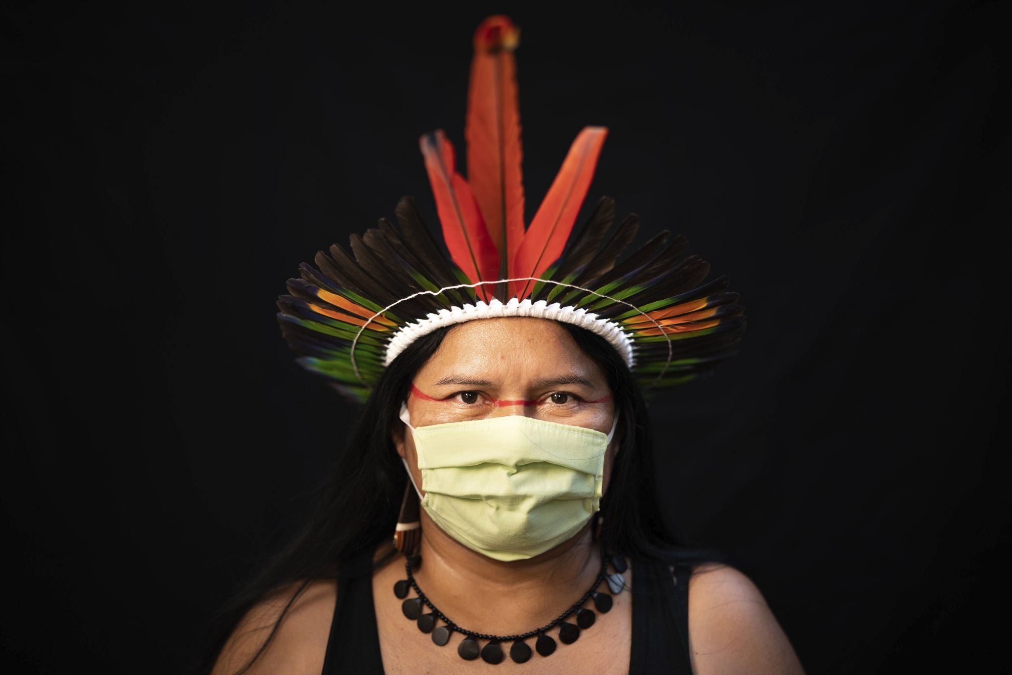 Dilza, 39, of the Sateré Mawé indigenous ethnic group, poses for a portrait wearing the traditional dress of her tribe and a face mask amid the spread of the new coronavirus in Manaus, Brazil, Wednesday, May 27, 2020. Image by Felipe Dana / AP Photo. Brazil, 2020.