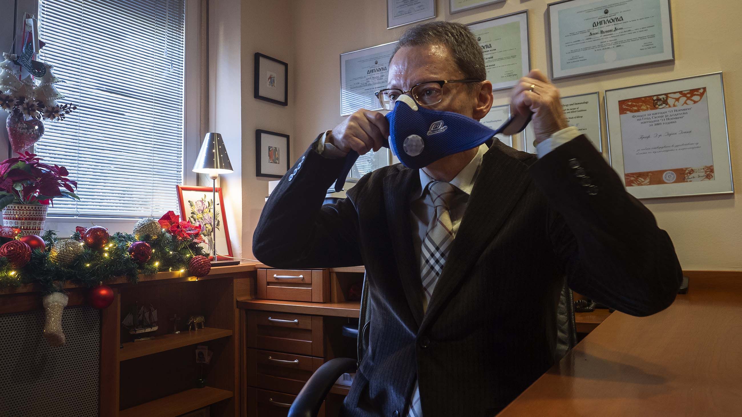Dr. Dejan Dokic is the director of the University Clinic of Pulmonology and Allergy in Skopje. Here he demonstrates a HEPA mask, which he recommends to his patients — and sometimes uses himself when pollution is bad. Image by Larry C. Price. Macedonia, 2018.