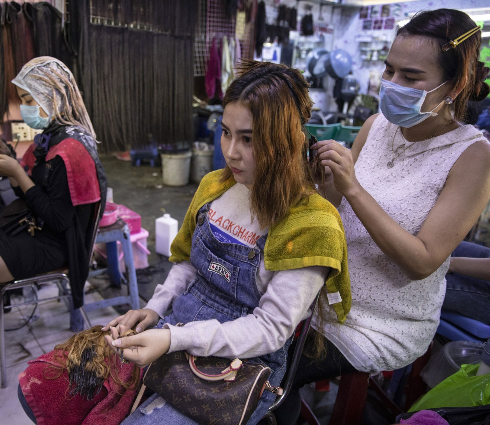 Hair salon owner Meyly Heng places a hair extension on a customer in Phnom Penh. Image by Paula Bronstein. Cambodia, 2019.