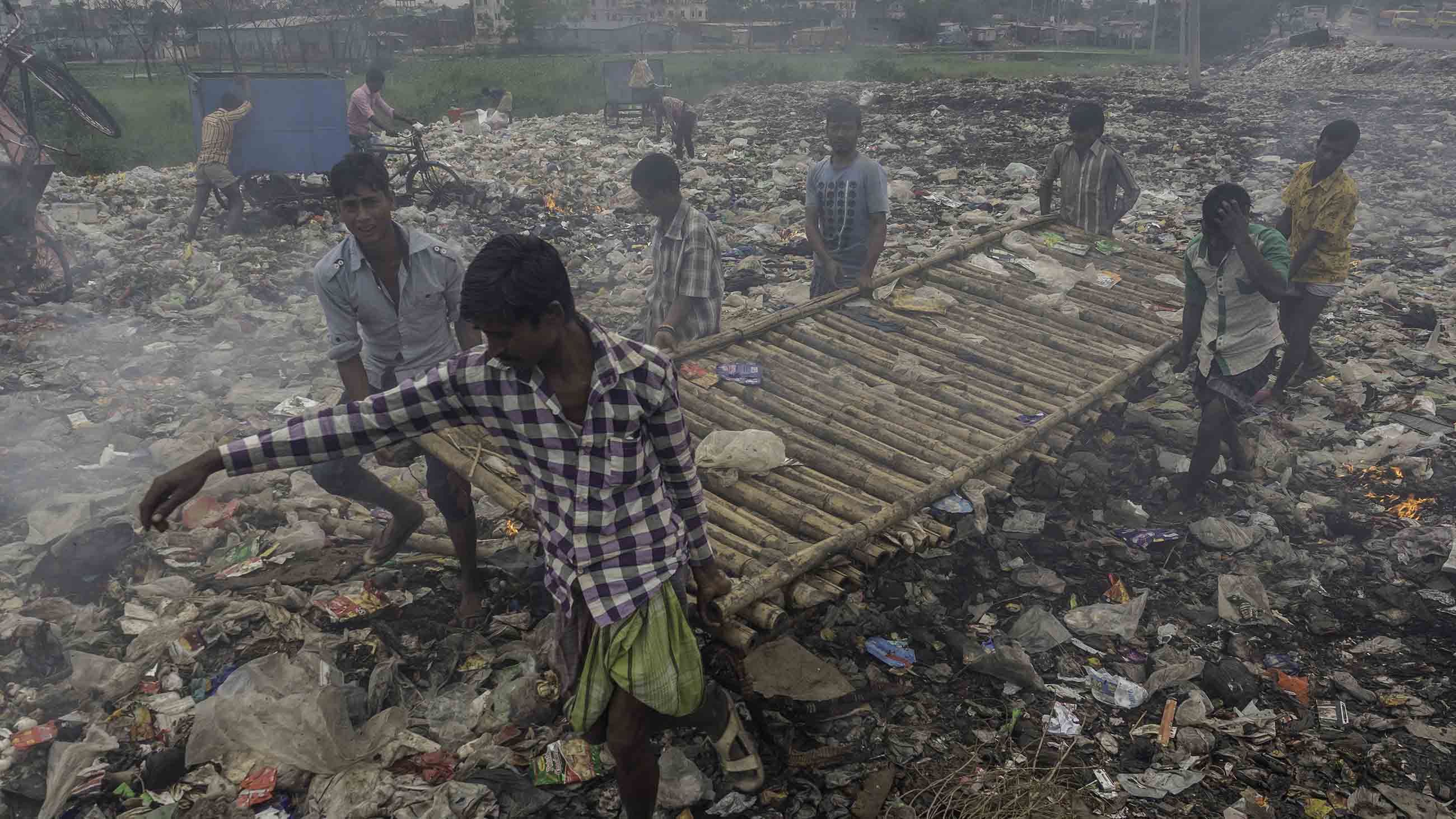 With little in the way of collection services, trash is often found smoldering in the streets, adding to the ambient waves of particulate matter. Image by Larry C. Price. Bangladesh, 2018.