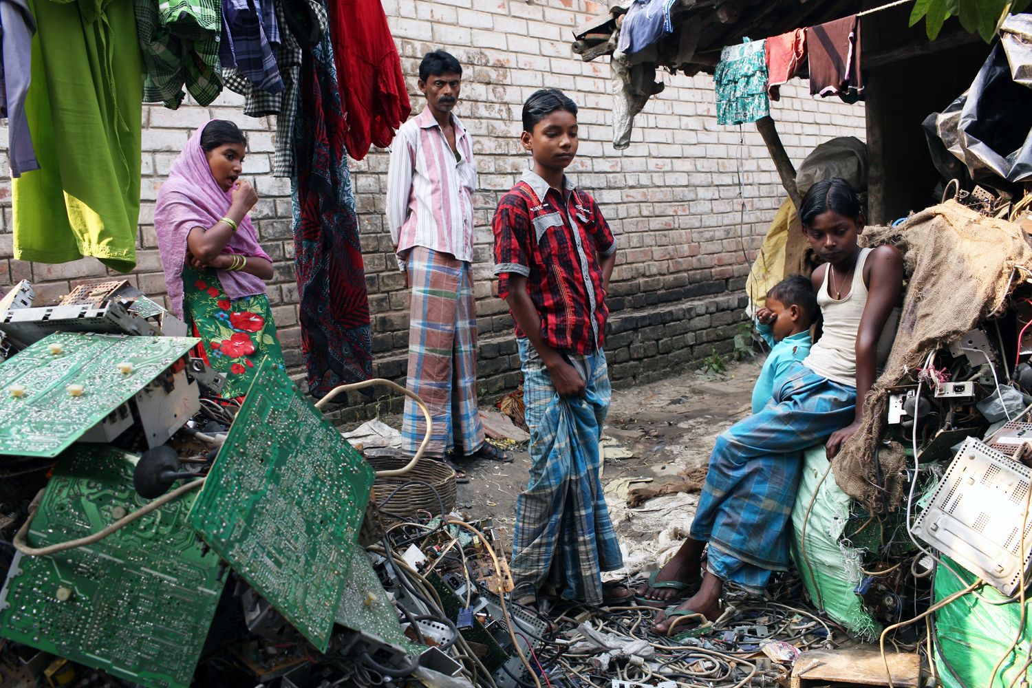 Villagers stand among piles of e-waste in the village of Sangrampur, located south of Kolkata in northeast India. Globally, an estimated 50 million tons of e-waste are produced annually, and much of it ends up in countries like India. Image by Sean Gallagher. India, 2013.