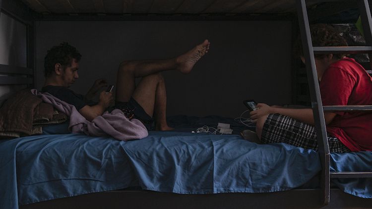 Two of Milagros Cancel Ruiz’s three children, Edwin Sanabria (left) and Giovanni Cancel (right) in the bed they share in the living room. Image by Hiram Alejandro Durán / Center for Investigative Journalism. United States, 2020.