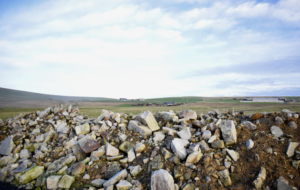 A view of farms near Billia Croo on the Orkney mainland. Much of the inland portion of the main island is agricultural. Sheep and fields are common sights, as are small domestic wind turbines connected to individual houses and farms. Image by Maggie More. United Kingdom, 2020.