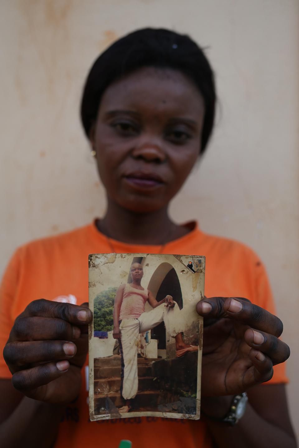 Larissa shows an undated photo of herself with her head shaved for Séléka training. “There were many, many women,” she explained in Bangui on September 24. “They taught us how to hold and use a gun, how to kill someone and how to take over other people’s belongings.” Image by Cassandra Vinograd. Central African Republic, 2017.