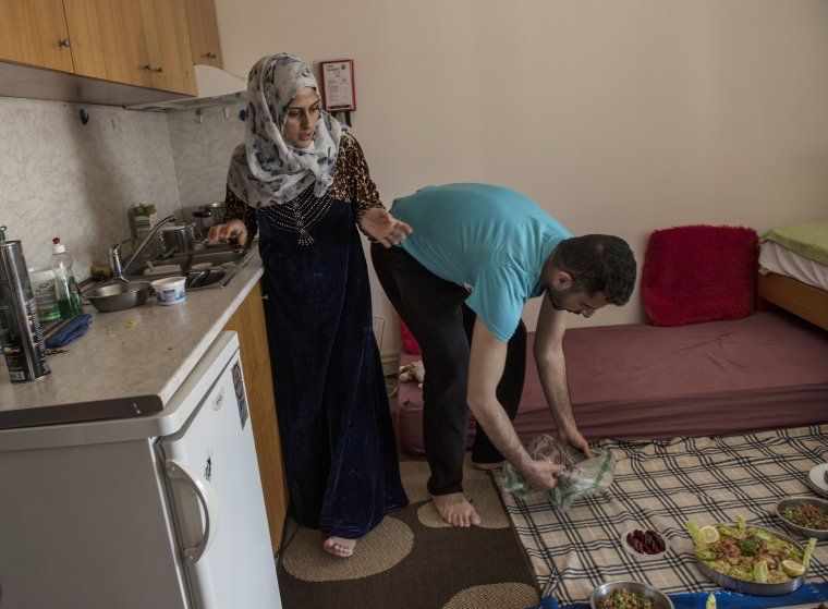 Noor Al Talaa, 22, and her husband, Yousuf Arsan, 27, prepare lunch at home with baby Rahaf, almost 6 months, at an apartment in Sidros, outside of Thessaloniki. Image by Lynsey Addario. Greece, 2017.