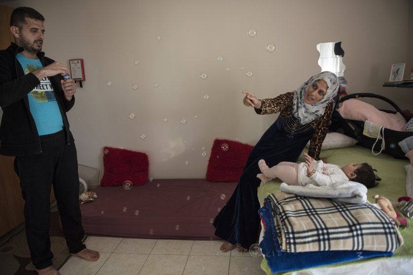 Noor Al Talaa, 22, and her husband, Yousuf Arsan, 27, entertain baby Rahaf, almost 6 months, at an apartment in Sidros. Image by Lynsey Addario. Greece, 2017.