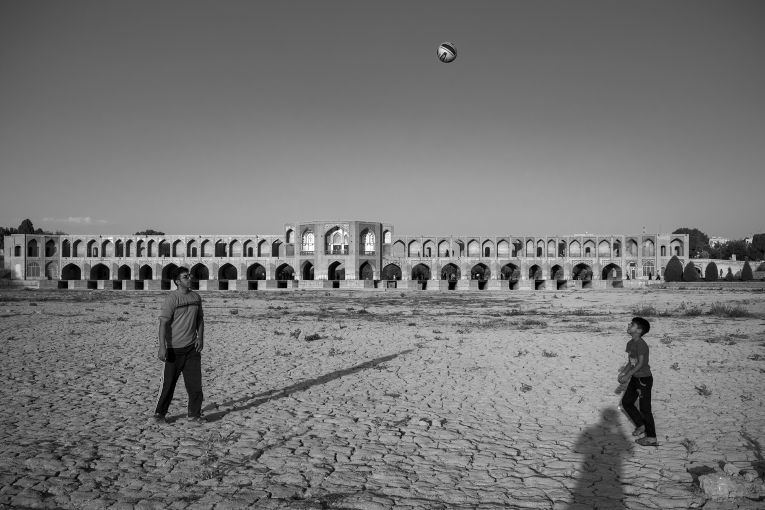 Playing inside the dried riverbed of the Zayandeh River near the Khajou bridge in EIsfahan. Image by Ako Salemi. Iran, 2016.