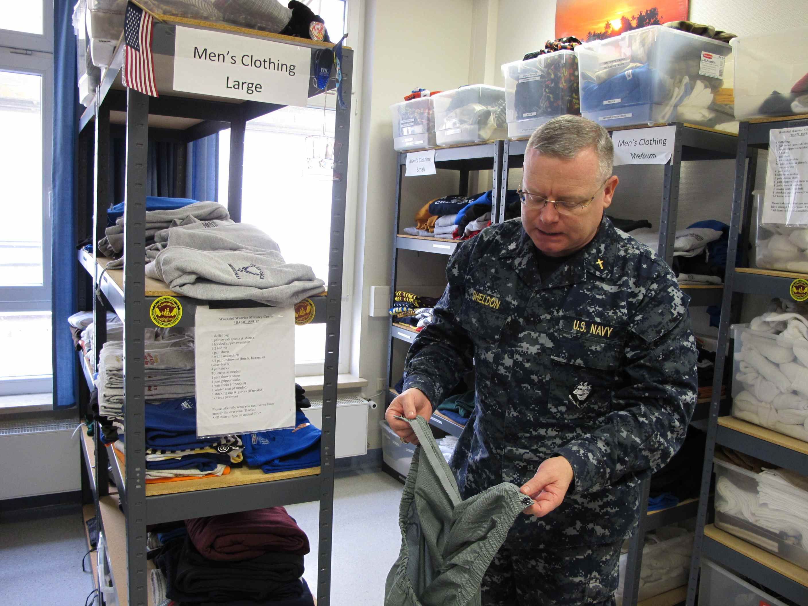 Cmdr. Joseph Sheldon, a Navy chaplain, examines a pair of pants that have been taken apart and installed with Velcro so a wounded soldier can dress themselves. Image by Meg Jones. Germany, 2011.