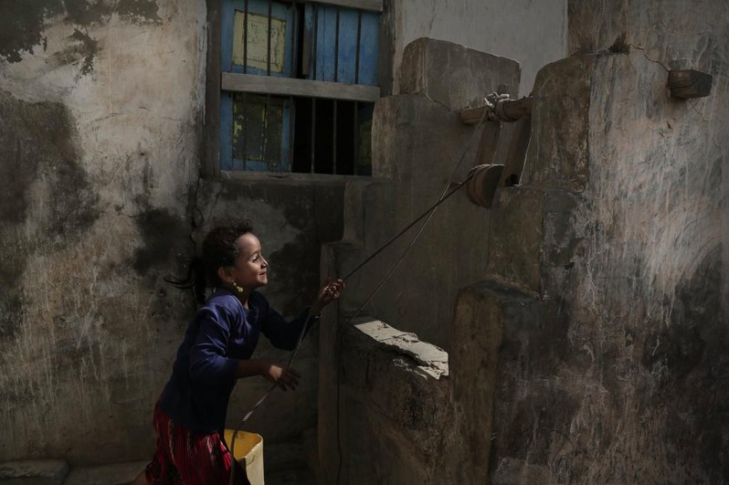 In this Feb. 12, 2018, photo, a girl pulls water from a well in the home of Ahmed al-Kawkabani, leader of the southern resistance unit in Hodeida, in al-Khoukha, Yemen. Image by Nariman El-Mofty. Yemen, 2018. 

