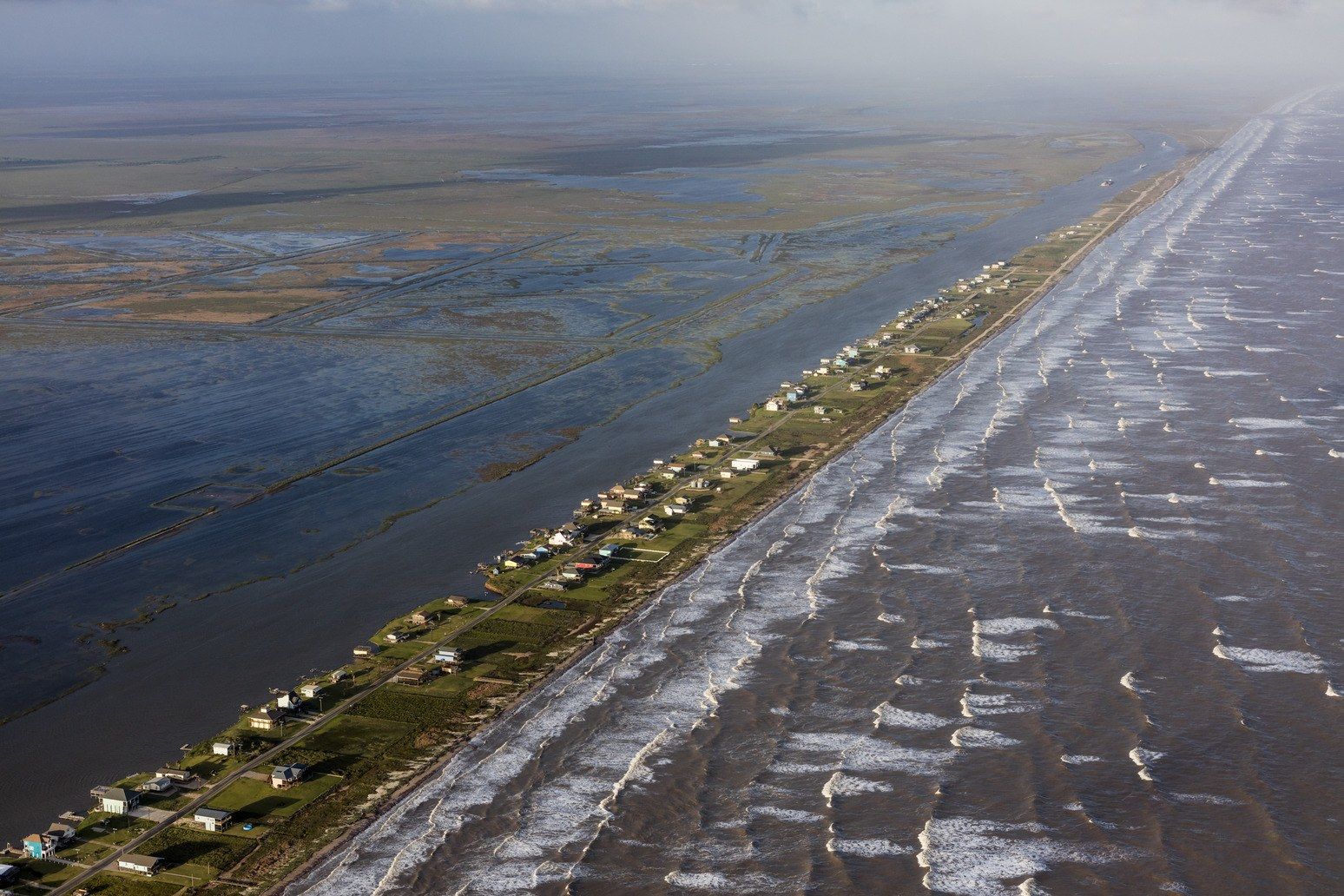 In Bay City, located between the Gulf of Mexico and the Intercoastal Waterway, building codes require new homes to be built thirteen feet above mean sea level—but that rule won’t prevent damage from a direct hit by a storm and, with sea level rise, will become less effective every year. Image by Alex MacLean. Unites States, 2017.