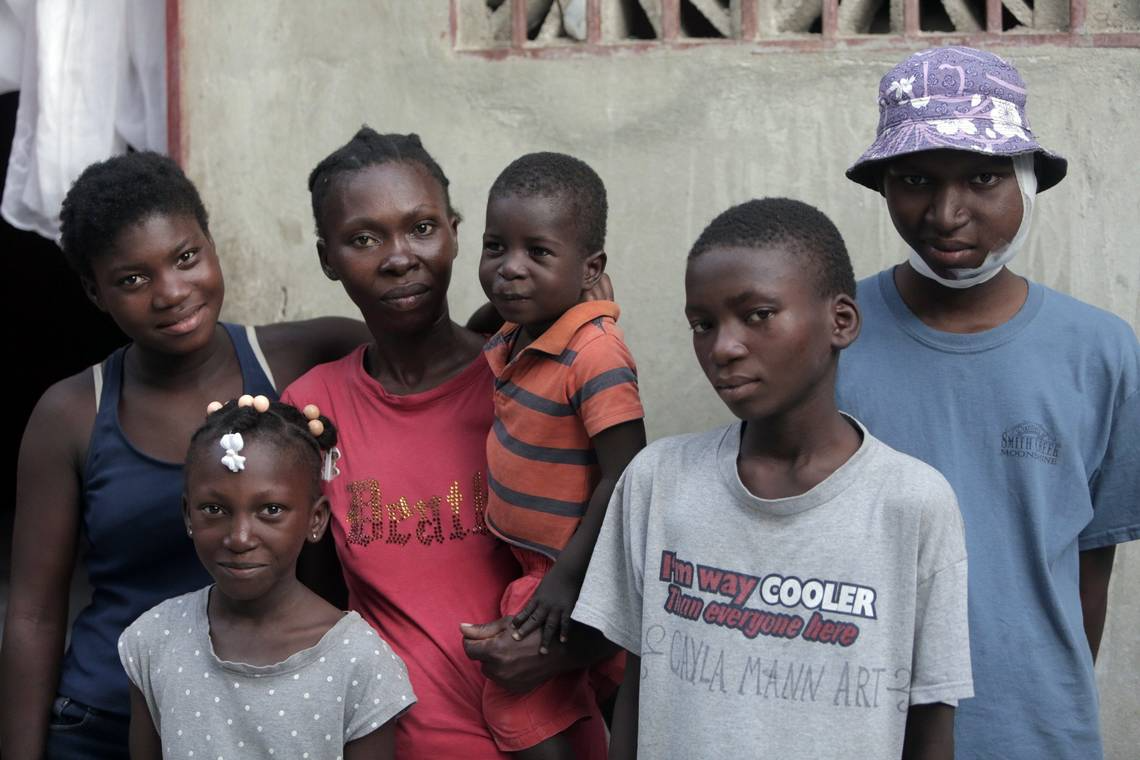 Djooly Jeune, 17, (on the end) was finally diagnosed with Burkitt’s lymphoma earlier this year after several doctors told his mother he had a dental problem. His illness weighs heaving on siblings, Estherlineda, 14, Josieanne, 7, Moise, 3 (being held by mom Angena Altidor) and Jhony Jeune. Image by José A. Iglesias. Haiti, 2018.