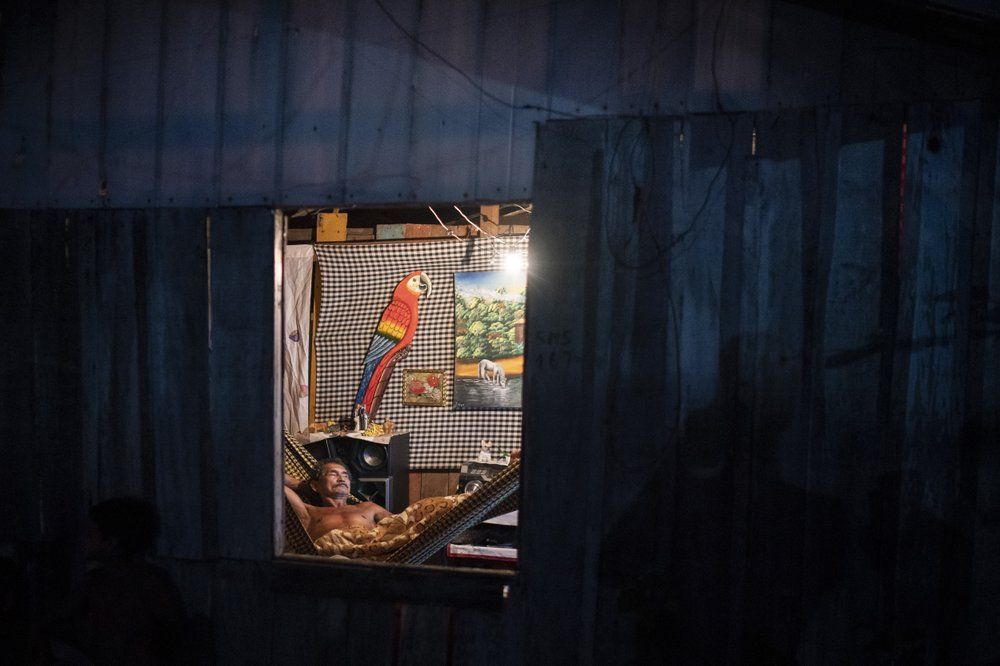 A man rests in a hammock inside his home at the Park of Indigenous Nations community, where many residents fell ill with symptoms of the new coronavirus, in Manaus, Brazil, Sunday, May 10, 2020. Image by Felipe Dana / AP Photo. Brazil, 2020.
