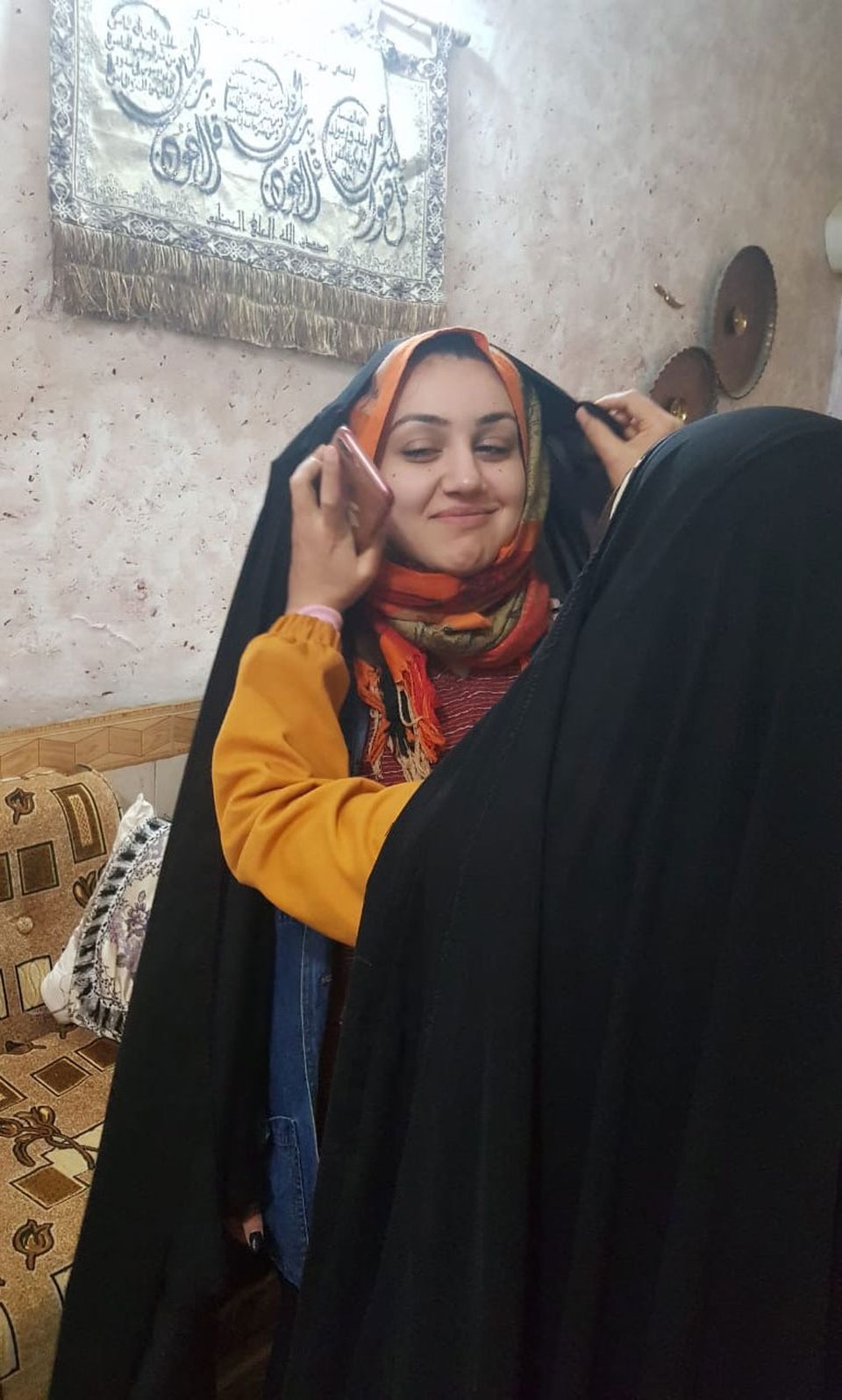 Samira Sibte helps her niece, Zahra Ahmad, put on an abaya in Najaf, Iraq. Image courtesy of Ahmad family. Iraq, 2019.