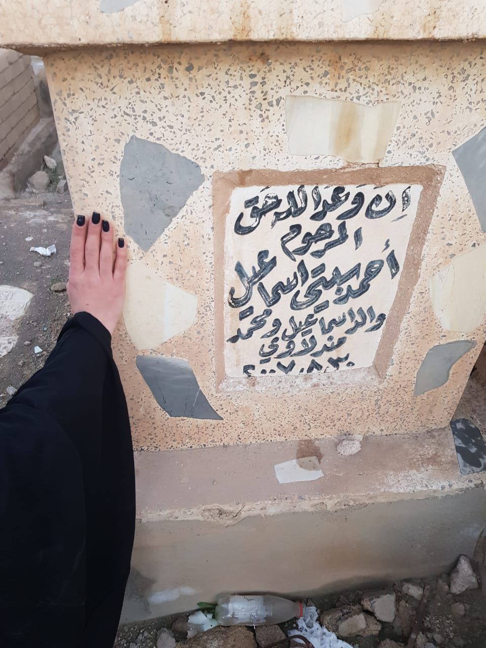 Zahra Ahmad places her hand over her grandfathers grave in Wadi-us-Salaam, the world's largest grave, in Najaf, Iraq.