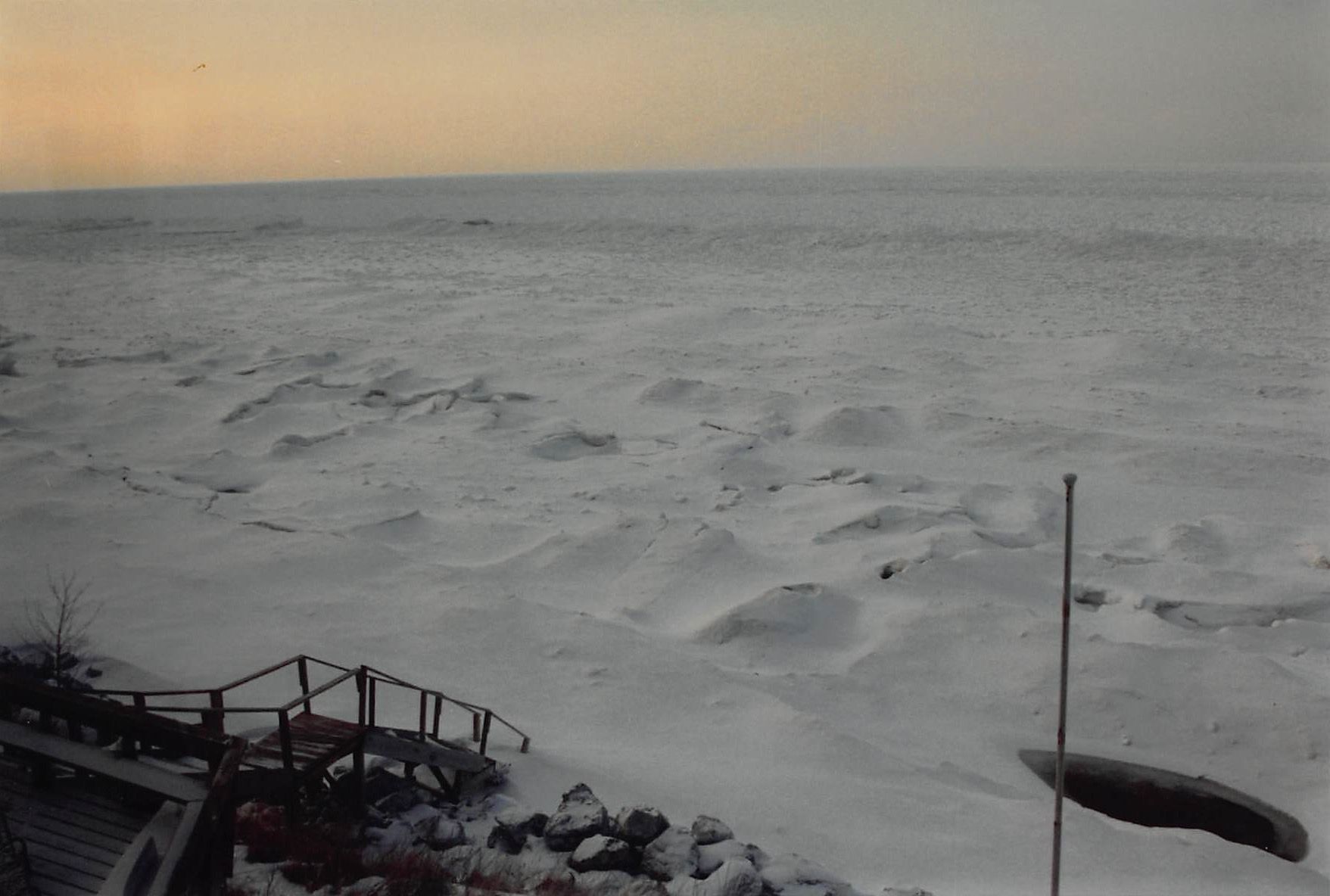 This is a photo of the ice shelf extending out from the beach at Nancy Schwab's vacation home in the early 1990s. As the Earth warms, that ice shelf is not there to protect the beaches and dunes along Lake Michigan from erosion. Courtesy of Nancy Schwab.