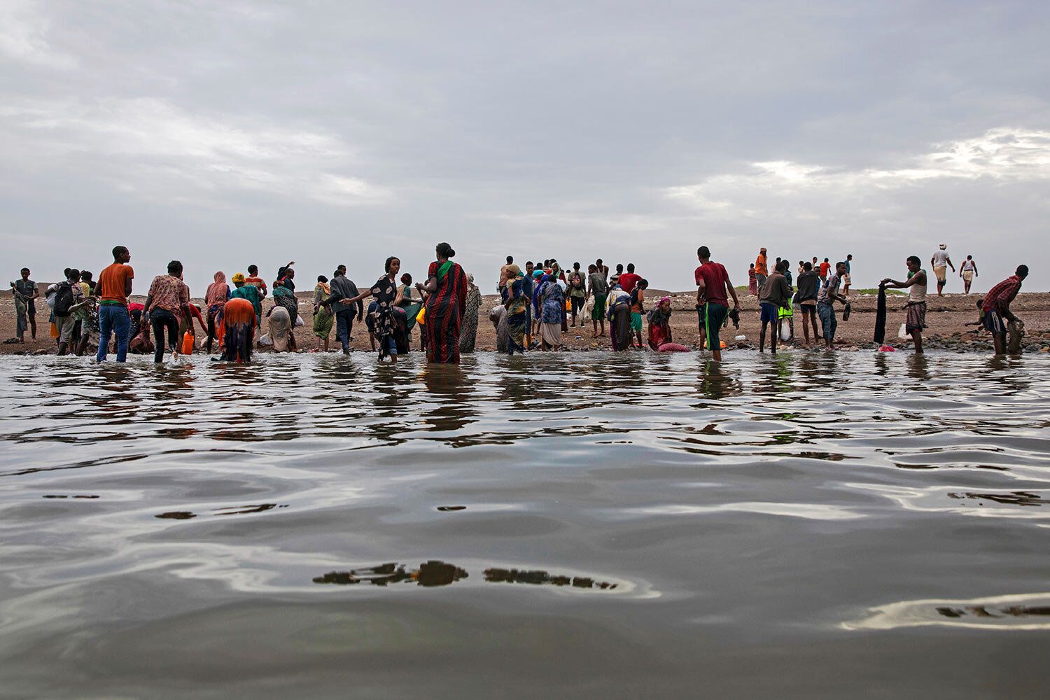 In this July 26, 2019 photo, Ethiopian migrants walk on the shores of Ras al-Ara, Lahj, Yemen, after disembarking from a boat. According to the U.N.'s International Organization for Migration the number of women making the trip jumped from nearly 15,000 in 2018 to more than 22,000 in 2019. The number of girls had an enormous increase, quadrupling from 2,075 to 8,360. Despite the many risks – smugglers' exploitation, hunger, drowning – they are undaunted. Image by Nariman El-Mofty / AP Photo. Yemen, 2019.