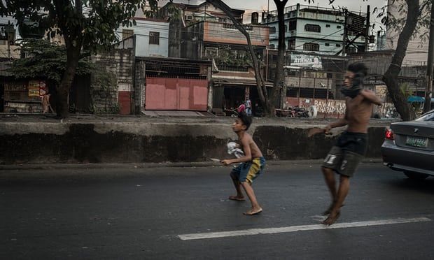 Boys, armed with a knife and a rusty machete, emerge from a slum in Tondo, Manila, to pursue a rival across a highway, through rush-hour traffic to attack him. Image by James Whitlow Delano. Philippines, 2018. 
