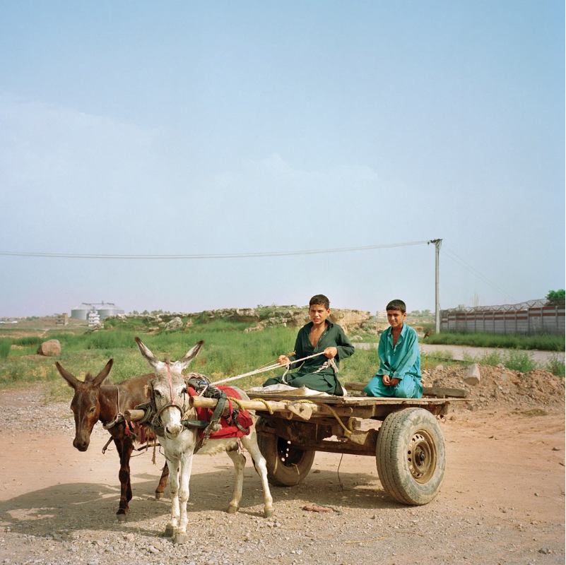 Boys at the I-12 settlement ride a traditional donkey carriage used to transport goods. Image by Sara Hylton. Pakistan, 2018.