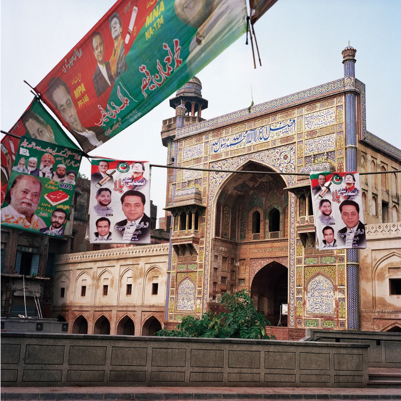 In the lead-up to national elections, political signs were scattered everywhere on the streets. Here, Pakistan Tehreek-E-Insaf (PTI) and Muttahida Majlis-E-Amal (MMA) signs hang in front of the Wasir Khan Mosque in the walled city of Lahore. The Pakistan cricket legend Imran Khan became the prime minister of Pakistan and led PTI to emerge as the single largest party in parliament last year. Image by Sara Hylton. Pakistan, 2018.