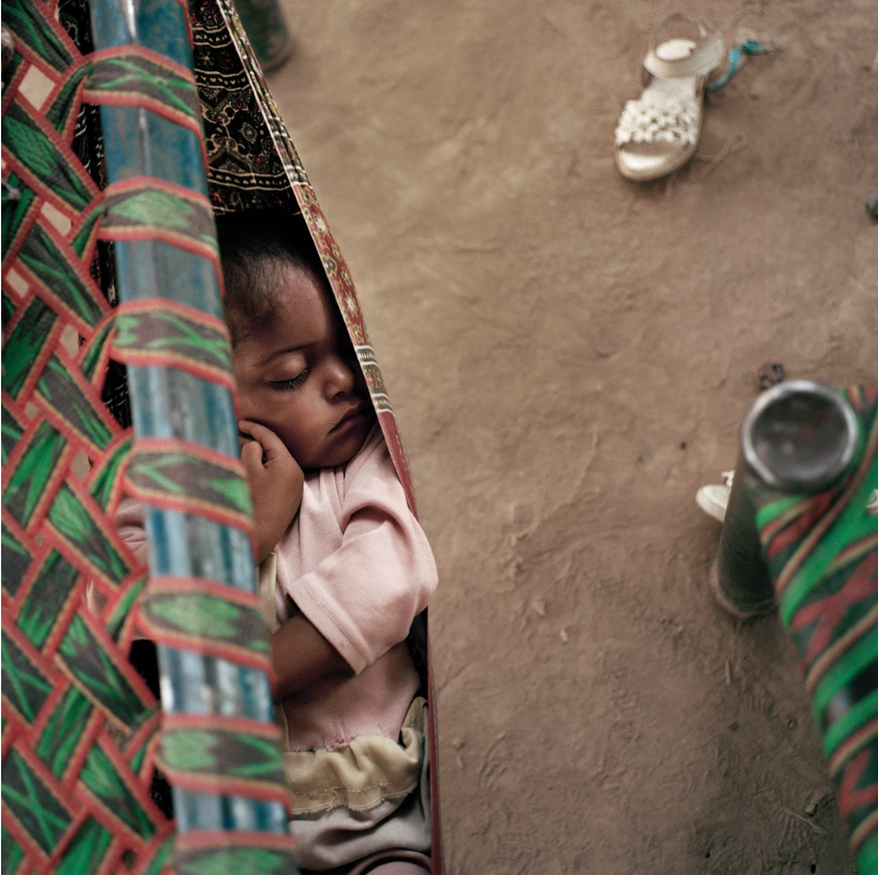 A little girl sleeps in a colony in Islamabad for landless Pakistanis. Like Afghans, Pakistanis living in informal settlements are vulnerable to discrimination and abuse, and in recent years several areas housing both Pakistanis and Afghans have been demolished to make way for development and high-rise apartment complexes. Image by Sara Hylton. Pakistan, 2018.