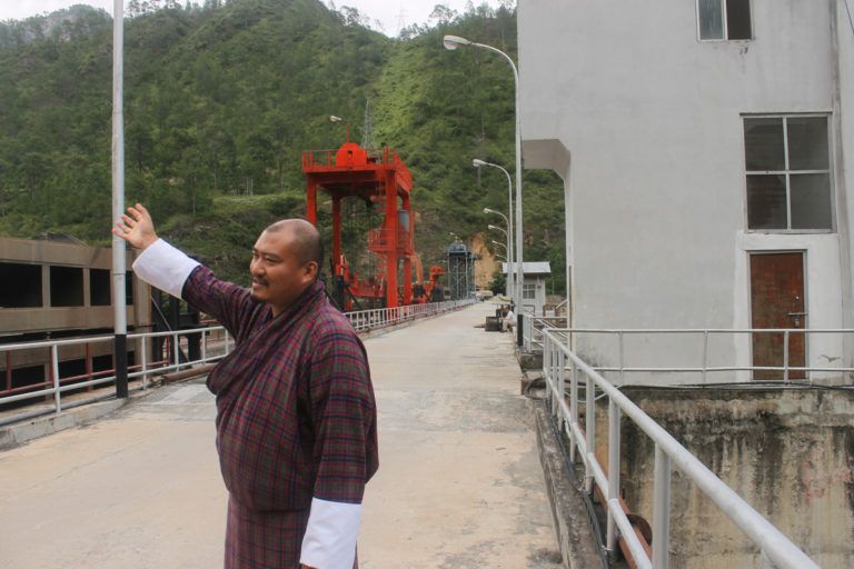 Zangpo, Superintending Engineer of Kurichhu Hydropower Plant in Mongar, eastern Bhutan, gestures downstream during a tour on top of the dam. Image by Emma Johnson. Bhutan, 2019.