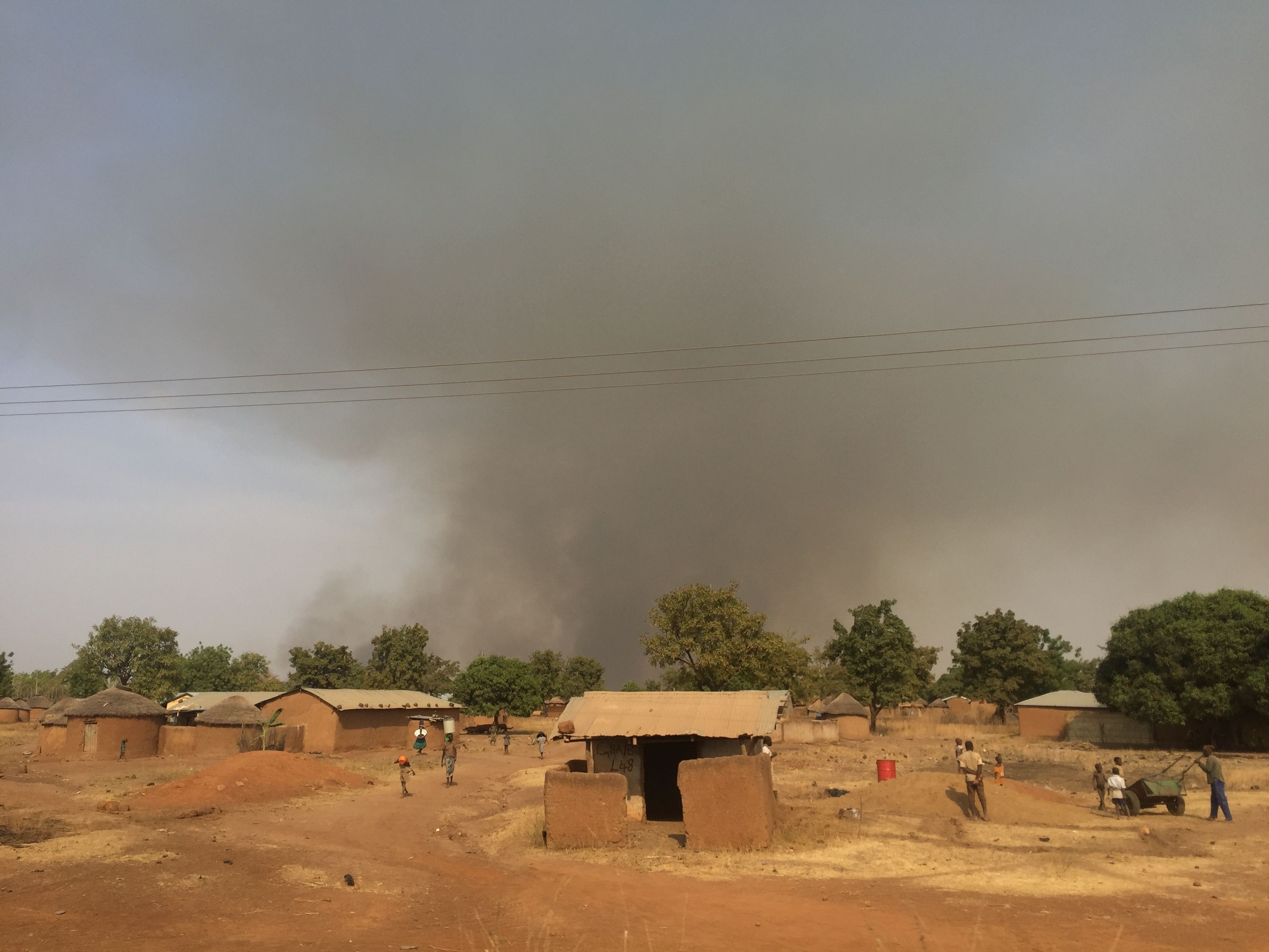 Bush fires burn behind a village in Yendi District. Image by Noah Fowler. Ghana, 2017.