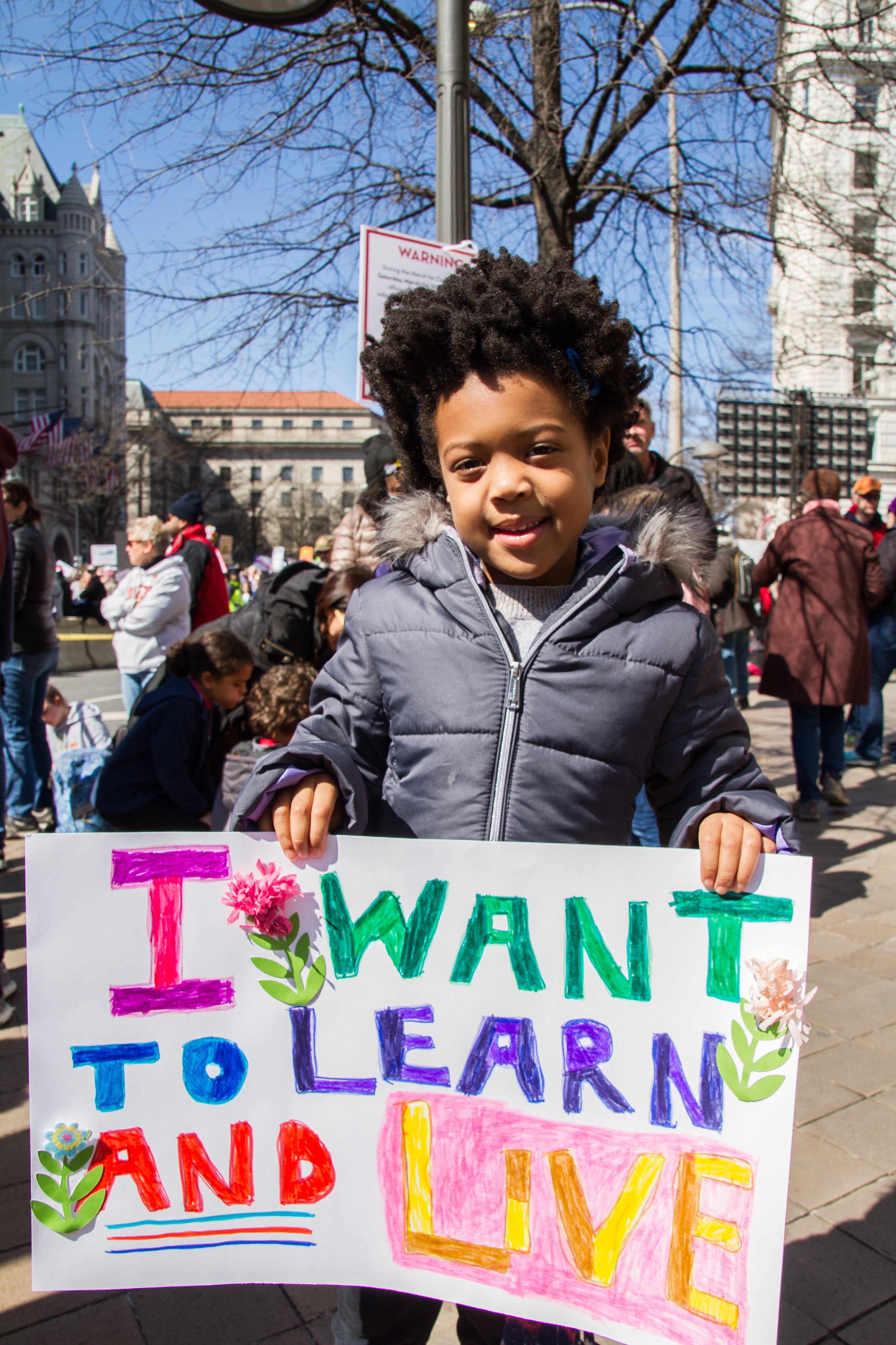 A student smiled, showing the 3D flowers on his sign at March For Our Lives. Image by Alyssa Sperrazza. United States, 2018.