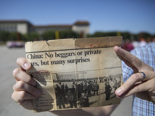 Kyle Munson, of the Des Moines Register, holds a clip of an article written by Register publisher David Kruidenier after his trip to China in 1979, in Tiananmen Square on Friday, Sept. 22, 2017, in Beijing. Image by Kelsey Kremer. China, 2017.