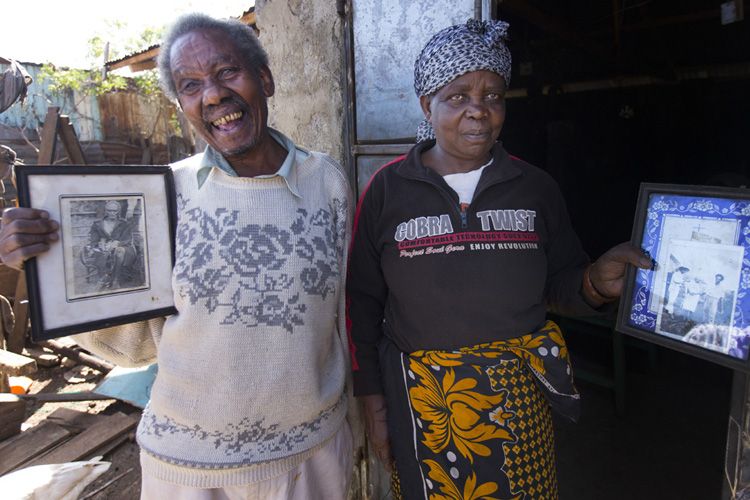 Paul Mugai Ngage (left) and his wife, Ann Wanjiku, proudly display photos of their ancestors at their home in the Kawangware slum. The couple and their extended family live with some of their children and grandchildren in a house with a corrugated metal roof and a yard filled with livestock, including sheep, goats, rabbits, ducks, dogs and chickens. Image by Mark Hoffman. Kenya, 2017. 