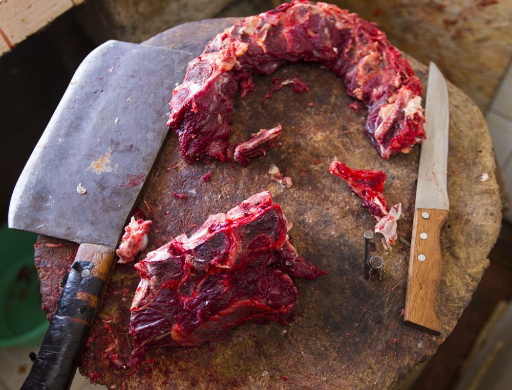 Beef is trimmed on a traditional stump. The stump can play host to harmful pathogens, so the International Livestock Research Institute encourages butcher shops to use steel instead. The owners, however, do not like how metal dulls their cutting tools. Image by Mark Hoffman. Kenya, 2017.