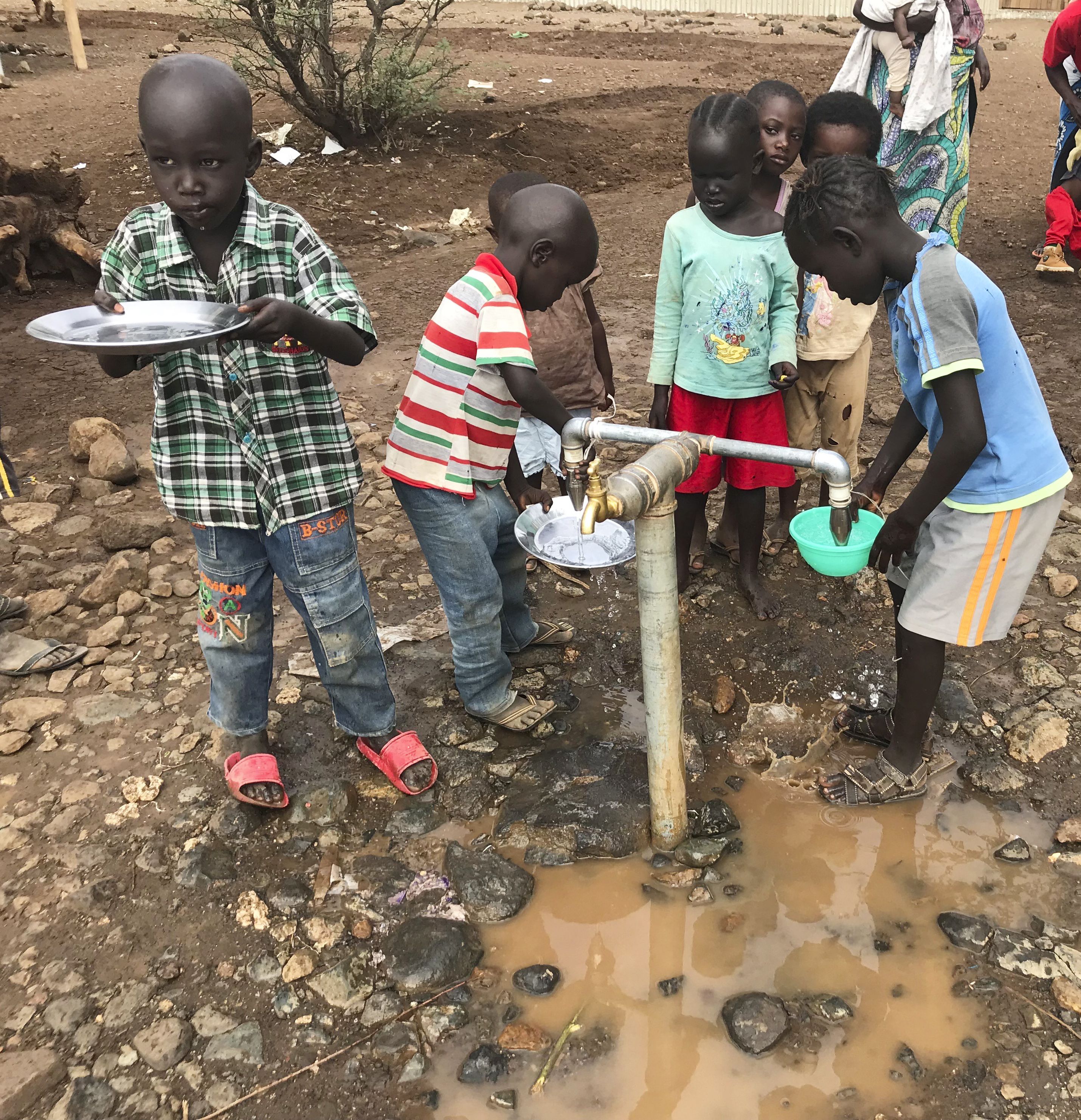 Children at Kalobeyei Friends School take a water break. The school’s 5,815 students meet in makeshift classrooms and sit on mats spread on dirt floors. Image by Jaime Joyce. Kenya, 2018.