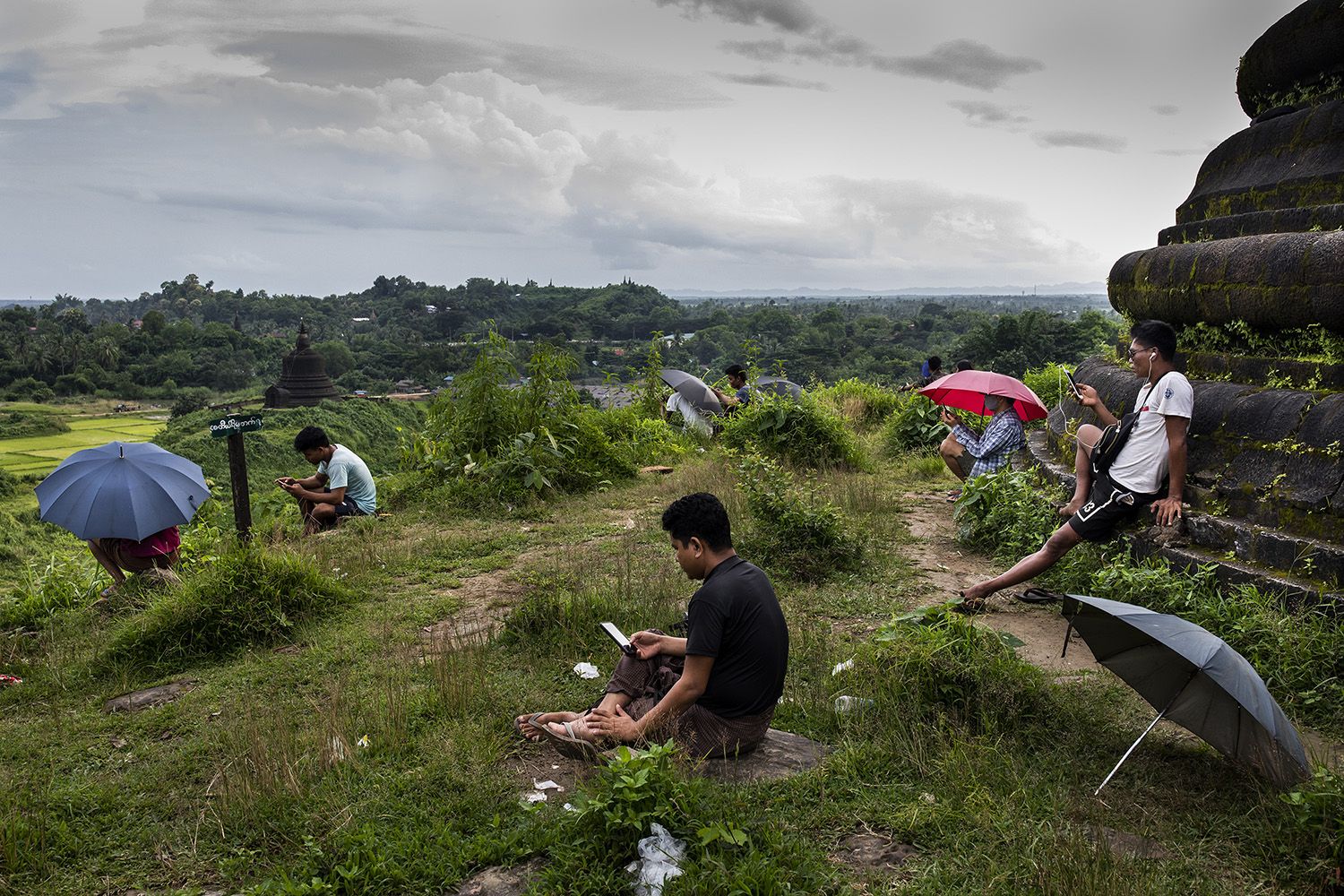 People sit on a hill to search for a 3G signal in Mrauk U, Myanmar, on Aug. 20. The government has blocked high-speed internet in the township since June 2019. Image by Hkun Lat/Foreign Policy. Myanmar, 2020.