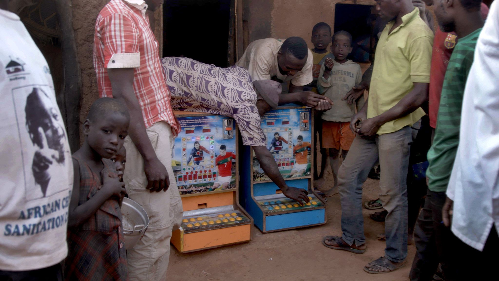 Villagers bring two gambling machines out from a hut in Zamashegu, in Ghana's Northern Region. Image by Noah Fowler. Ghana, 2017.