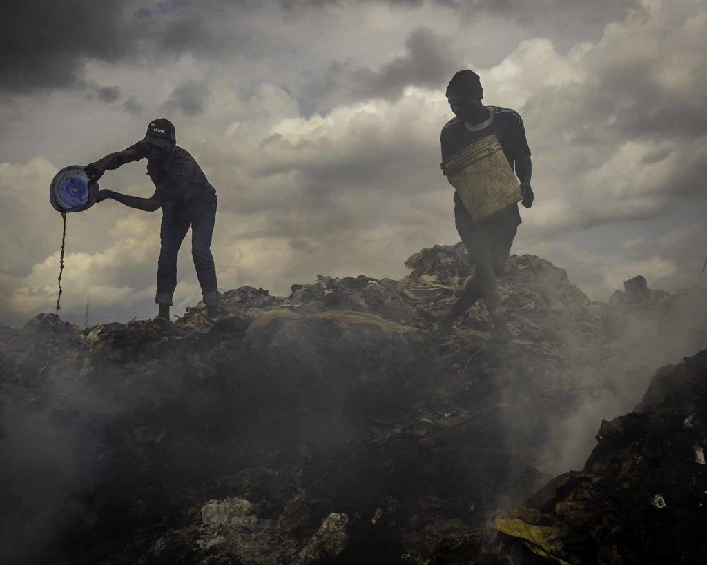 Landfill fires are incessant around Lagos, and locals make money by organizing small bucket brigades to fan out and tamp down smoldering spots. Occasionally, larger fire erupt that require the resources of local firefighters. Image by Larry C. Price. Nigeria, 2018.